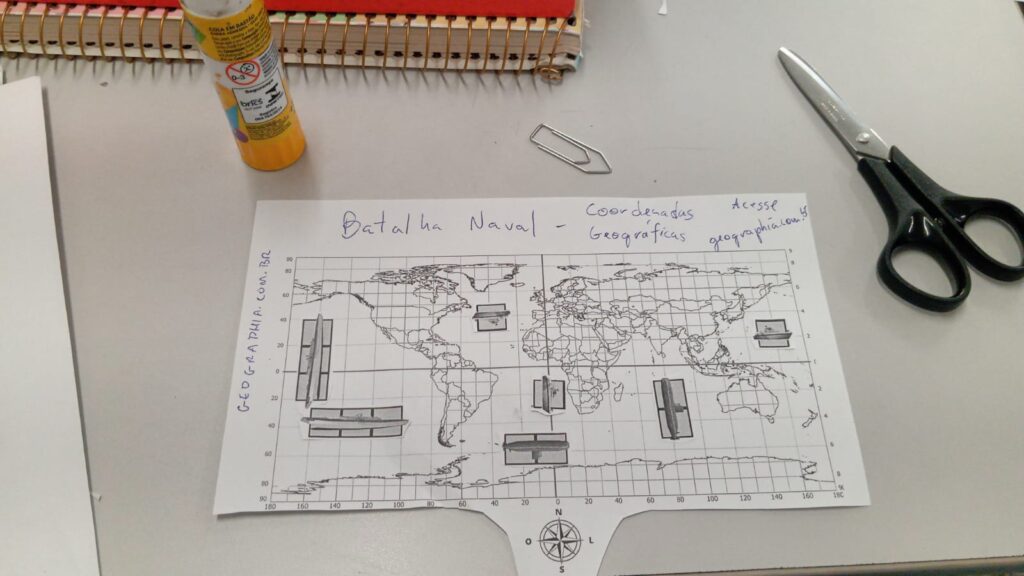 cola tesoura e tabuleiro de batalha naval com coordenadas geográficas